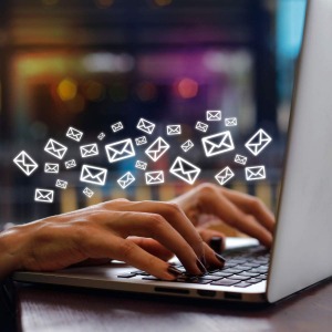 Bild auf dem ein Laptop zu sehen ist und aus dem Bildschirm fliegen grafisch dargestellte Briefe die das E-Mail Marketing widerspiegeln sollen.
