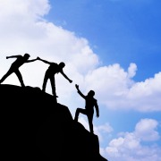 Personen auf einem Gipfel, wie sie sich gegenseitig helfen